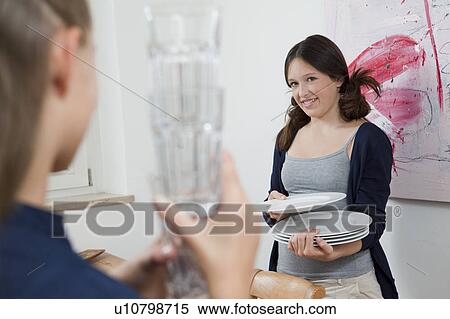 Stock Photography - Girls putting away dishes in kitchen. Fotosearch