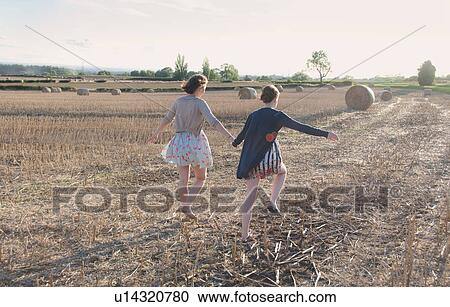 Stock Image - Girls running in hay field. Fotosearch