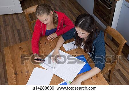 Stock Photo - Girls studying together in kitchen. Fotosearch