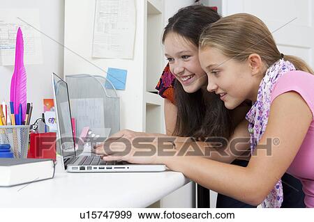 Girls using laptop together at desk View Large Photo Image Stock Photo - Girls using laptop together at desk. Fotosearch