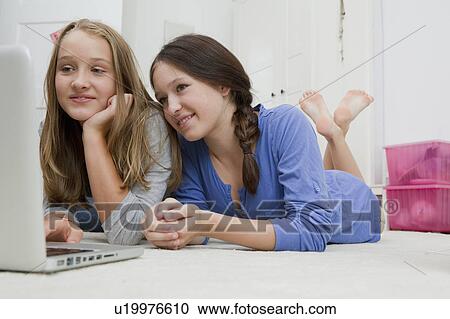 Girls using laptop together on floor View Large Photo Image Stock Image - Girls using laptop together on floor. Fotosearch