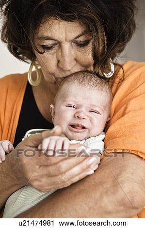 Grandmother cradling crying infant View Large Photo Image Stock Image - Grandmother cradling crying infant. Fotosearch