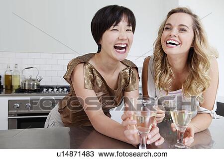 Stock Image - Laughing women drinking wine together. Fotosearch