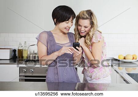 Stock Photograph - Laughing women using cell phone. Fotosearch