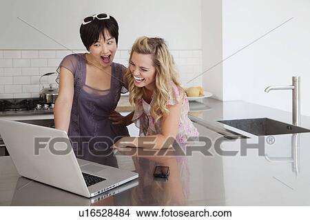 Laughing women using laptop in kitchen View Large Photo Image Picture - Laughing women using laptop in kitchen. Fotosearch