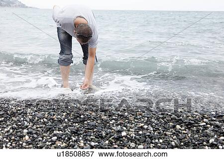 Man collecting pebbles on rocky beach View Large Photo Image Stock Photo - Man collecting pebbles on rocky beach. Fotosearch