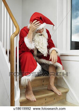 Stock Image - Man in Santa Claus suit sitting on steps. Fotosearch