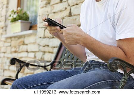 Man using cell phone on bench View Large Photo Image Stock Image - Man using cell phone on bench. Fotosearch