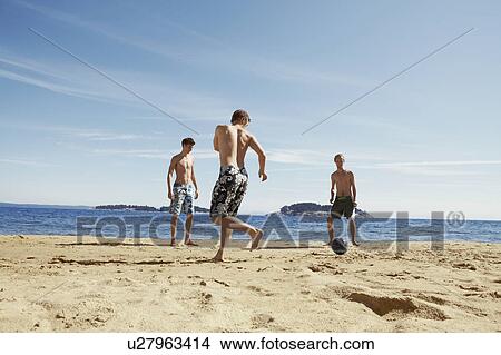 Picture - Men playing soccer on beach. Fotosearch