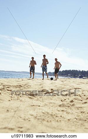 Stock Image - Men playing soccer on beach. Fotosearch