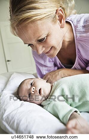 Stock Photo - Mother admiring infant on bed. Fotosearch