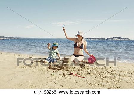 Stock Photograph - Mother and child building sandcastle. Fotosearch