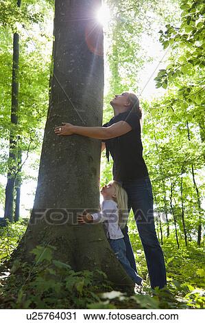 Mother and daughter hugging tree View Large Photo Image Stock Image - Mother and daughter hugging tree. Fotosearch