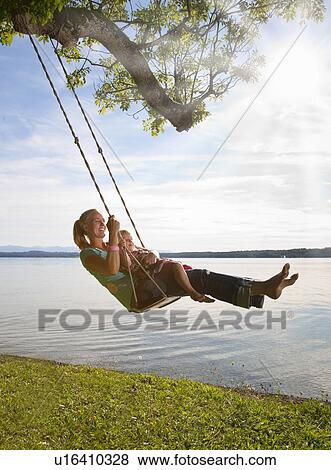 Stock Photo - Mother and daughter swinging from tree. Fotosearch