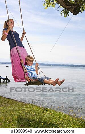 Mother and daughter swinging from tree View Large Photo Image Stock Photo - Mother and daughter swinging from tree. Fotosearch