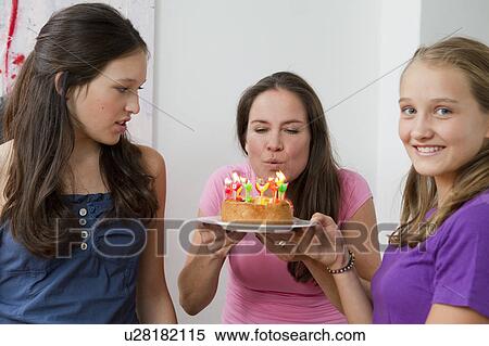 Stock Photography - Mother blowing out birthday candles. Fotosearch