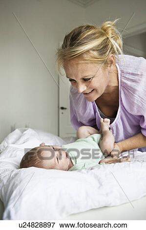 Stock Photo - Mother changing infant's diaper. Fotosearch