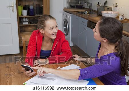 Stock Image - Mother helping daughter with homework. Fotosearch