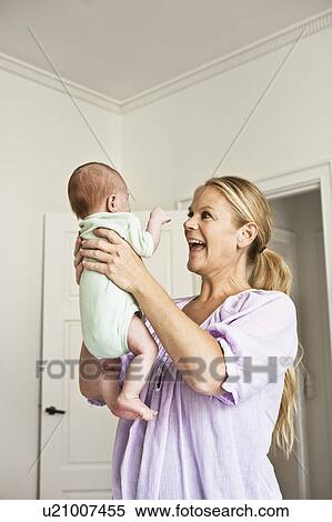Mother holding infant in bedroom View Large Photo Image Stock Photography - Mother holding infant in bedroom. Fotosearch