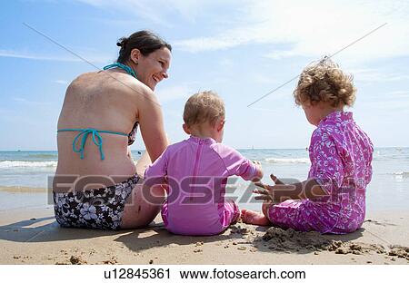 Stock Image - Mother playing on beach with girls. Fotosearch
