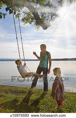 Mother playing with children on swing View Large Photo Image Stock Image - Mother playing with children on swing. Fotosearch