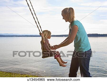 Mother pushing daughter on swing View Large Photo Image Stock Photography - Mother pushing daughter on swing. Fotosearch