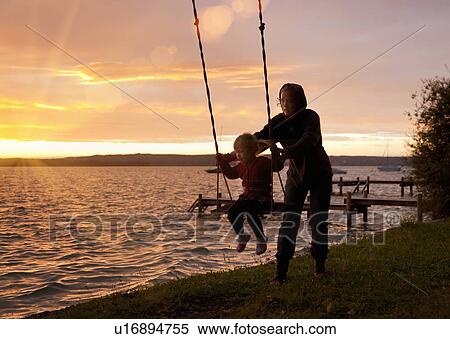Mother pushing daughter on swing View Large Photo Image Stock Photography - Mother pushing daughter on swing. Fotosearch