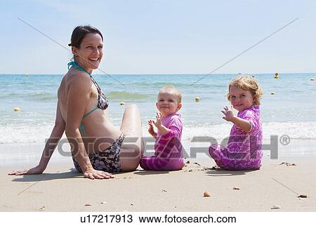 Mother sitting on beach with daughters View Large Photo Image Stock Image - Mother sitting on beach with daughters. Fotosearch