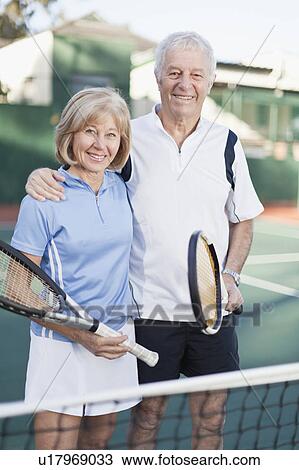 Older couple standing on tennis court View Large Photo Image Stock Image - Older couple standing on tennis court. Fotosearch