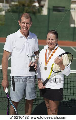 Older couple with trophy on tennis court View Large Photo Image Stock Image - Older couple with trophy on tennis court. Fotosearch