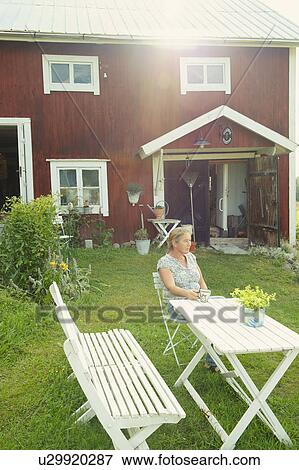 Older woman having coffee in backyard View Large Photo Image Stock Photo - Older woman having coffee in backyard. Fotosearch