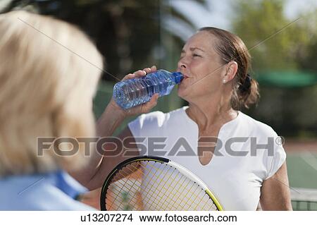Older woman having water on tennis court View Large Photo Image Picture - Older woman having water on tennis court. Fotosearch