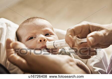 Parent feeding infant with syringe View Large Photo Image Stock Photo - Parent feeding infant with syringe. Fotosearch