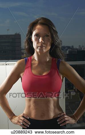 Stock Image - Runner standing on urban rooftop. Fotosearch
