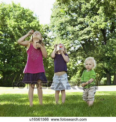 Sisters blowing bubbles with brother View Large Photo Image Stock Photograph - Sisters blowing bubbles with brother. Fotosearch