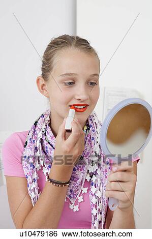Stock Photograph - Smiling girl applying lipstick in mirror. Fotosearch