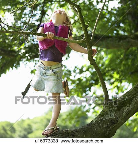 Stock Photo - Smiling girl climbing tree. Fotosearch