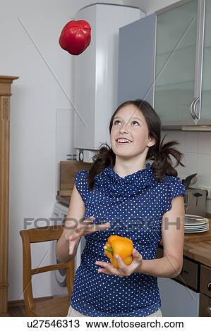Stock Image - Smiling girl juggling bell peppers. Fotosearch
