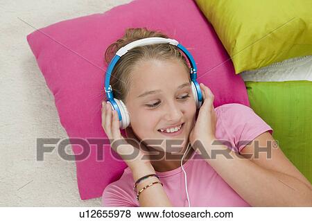 Smiling girl listening to headphones View Large Photo Image Stock Photo - Smiling girl listening to headphones. Fotosearch
