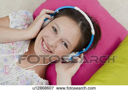 Smiling girl listening to headphones View Large Photo Image Stock Photo - Smiling girl listening to headphones. Fotosearch
