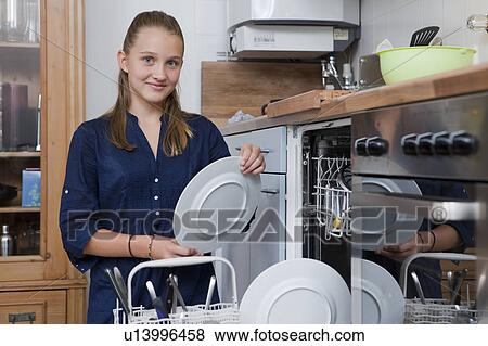 Stock Photo - Smiling girl loading dishwasher. Fotosearch