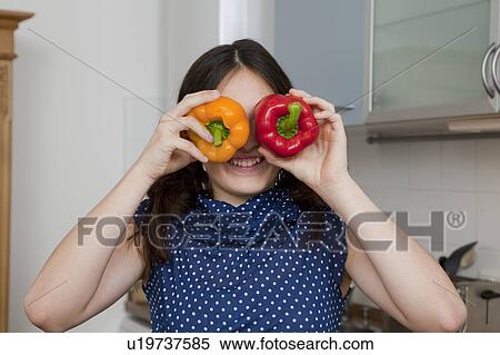 Stock Photography - Smiling girl playing with bell peppers. Fotosearch