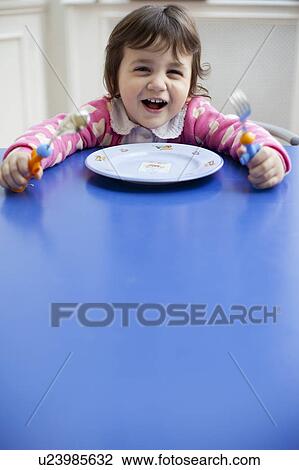 Smiling girl sitting at table View Large Photo Image Stock Image - Smiling girl sitting at table. Fotosearch