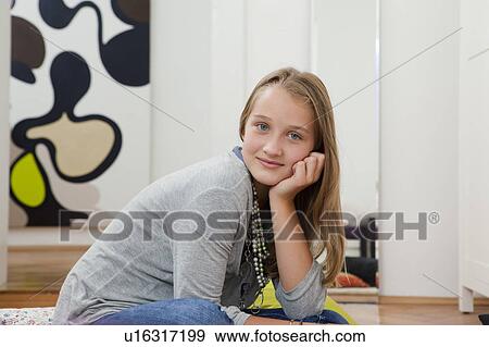 Stock Photo - Smiling girl sitting with chin in hand. Fotosearch