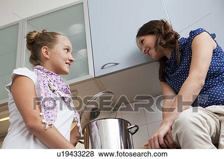 Stock Photo - Smiling girls cooking in kitchen. Fotosearch