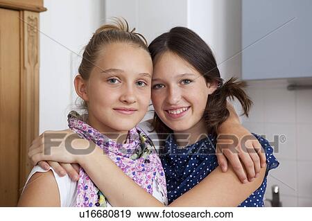 Smiling girls hugging in kitchen View Large Photo Image Stock Photo - Smiling girls hugging in kitchen. Fotosearch