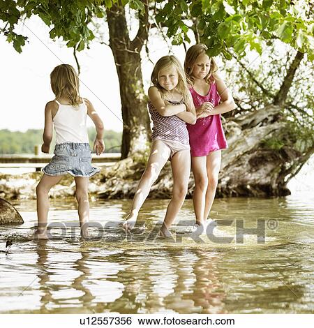 Stock Photograph - Smiling girls playing in lake. Fotosearch