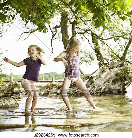 Stock Photography - Smiling girls playing in lake. Fotosearch