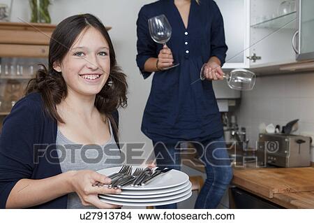 Picture - Smiling girls putting away dishes. Fotosearch