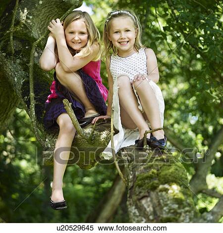 Smiling girls sitting in tree View Large Photo Image Stock Photography - Smiling girls sitting in tree. Fotosearch